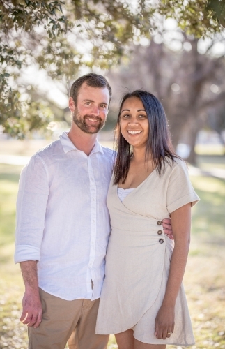 Caucasian husband standing with arm around aboriginal wife - Australian Stock Image
