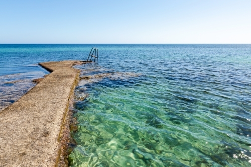 cement path to steps into blue sea