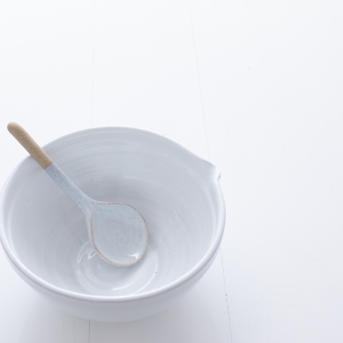 Ceramic mixing bowl and spoon on white background