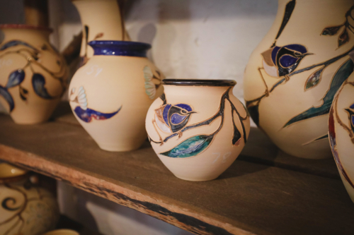 Ceramic vases with hand-painted florals on a rustic wooden shelf - Australian Stock Image