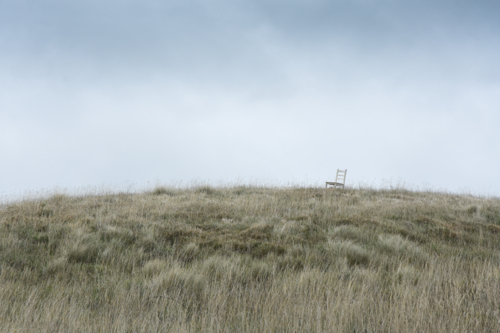Chair on grassy hill with grey sky - Australian Stock Image