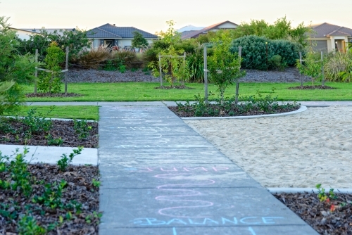 Chalk drawings on the pavement at a play park at dusk - Australian Stock Image
