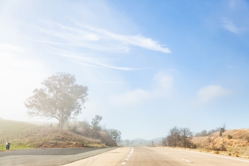 Changing weather conditions on highway sunlight and fog - Australian Stock Image