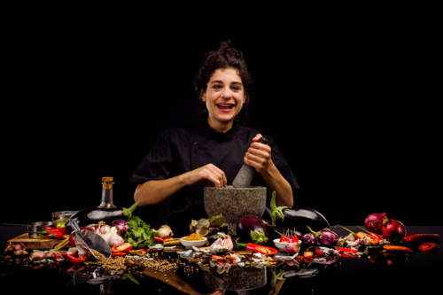Chef portrait, pounding spices with a mortar and pestle, making curry - Australian Stock Image