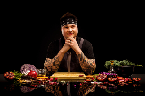 Chef portriat, with colourful salad ingredients, chopping board and knife - Australian Stock Image
