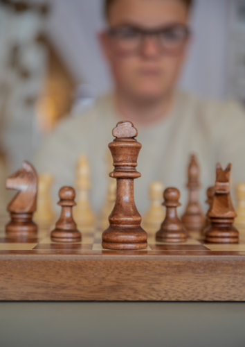 Chess board with teen boy in the background - Australian Stock Image