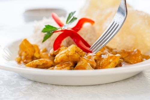Chicken curry served with rice garnished with red pepper and fresh parsley. - Australian Stock Image