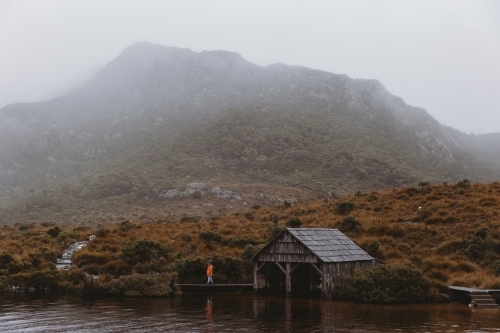 Child beside boat shed with mountain in background - Australian Stock Image