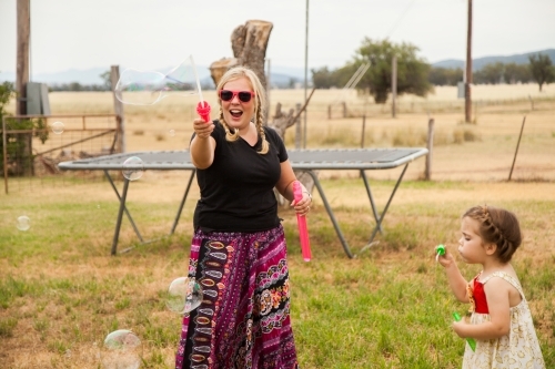 Child carer blowing bubbles outside - Australian Stock Image