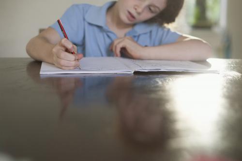 Child doing school homework at wooden desk.