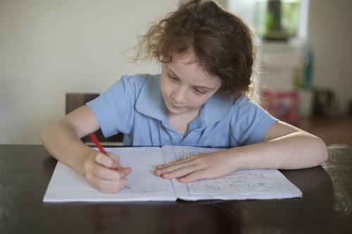 Child doing school homework at wooden desk.