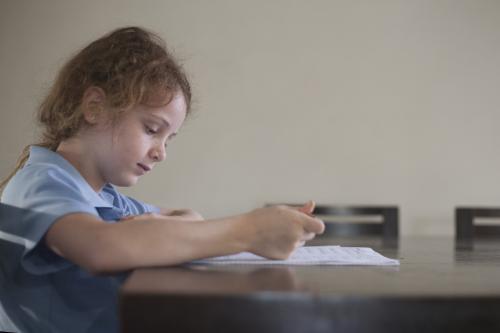 Child doing school homework at wooden desk. - Australian Stock Image