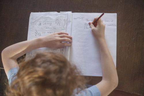 Child doing school homework at wooden desk. - Australian Stock Image