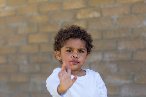 child frowning with hand up signalling stop - Australian Stock Image