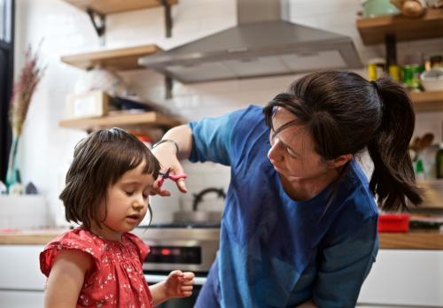 Child/girl getting her hair cut by her mother - Australian Stock Image
