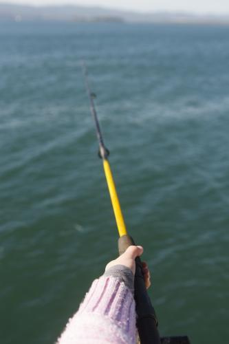 Child holding a yellow fishing rod over water
