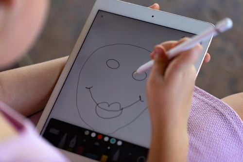 child holding digital tablet and drawing a happy face - Australian Stock Image