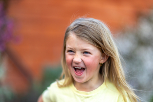 Child laughing joyfully during outdoor playtime - Australian Stock Image