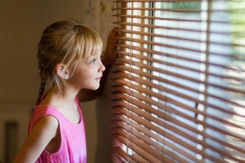 Child looking out through venetian blinds