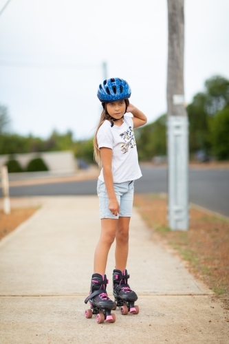 child  on roller skates on footpath of small  town - Australian Stock Image