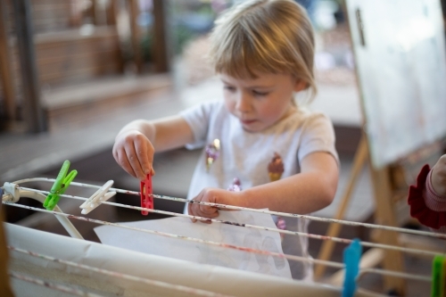 Child pegs a painting to dry at preschool