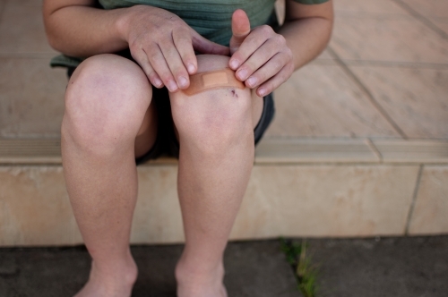 Child putting plaster on knee