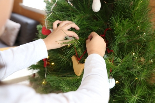 Child's hands decorating Christmas tree - Australian Stock Image
