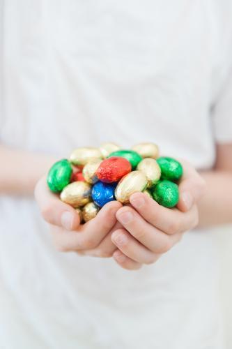 Child's hands holding coloured mini easter eggs - Australian Stock Image