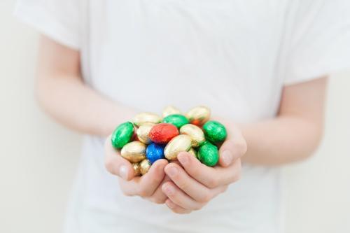 Child's hands holding coloured mini easter eggs - Australian Stock Image