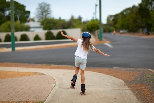 Child seen from behind rollerskating on footpath - Australian Stock Image