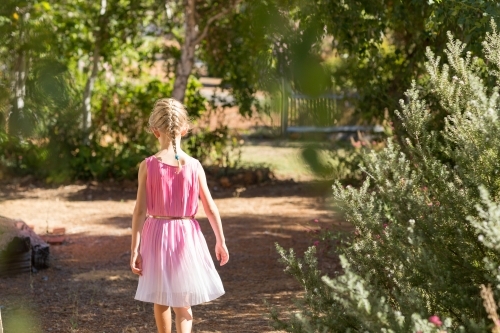 Child walking away on path through bushes