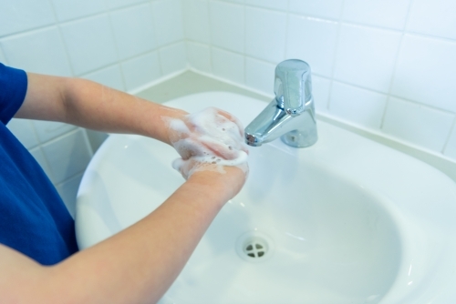 Child washing hands at sink