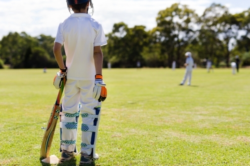 Child wearing pads waiting to bat during a game of cricket - Australian Stock Image