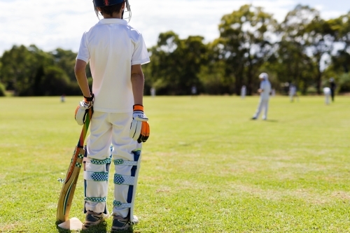 Child wearing pads waiting to bat during a game of cricket