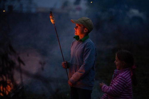 Children cook damper on bonfire - Australian Stock Image