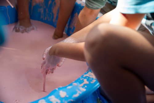 Children hands dripping with oobleck, cornstarch and water mixture, doing a science experiment - Australian Stock Image