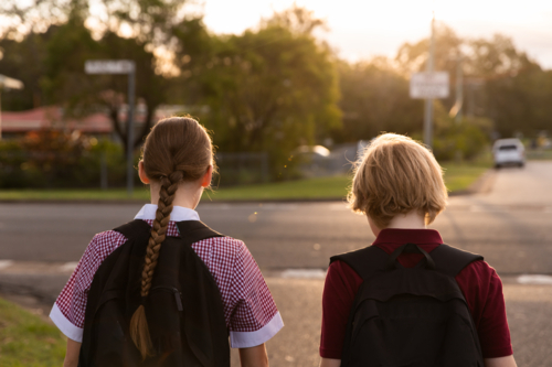 children in school uniform walking on a suburban street after school - Australian Stock Image