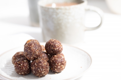 Chocolate protein balls on a white kitchen bench - Australian Stock Image