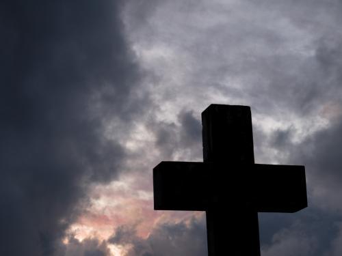 Christian cross silhouetted against a stormy sunset sky - Australian Stock Image
