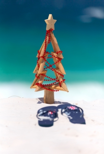 Christmas at the beach, sun, surf and leisure. A pair of thongs and small driftwood Christmas tree