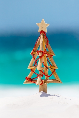 Christmas tree on idyllic white sandy beach with ocean background blur