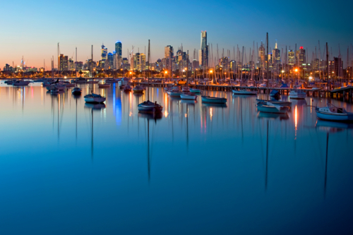 City skyline glowing over a calm marina at dusk - Australian Stock Image