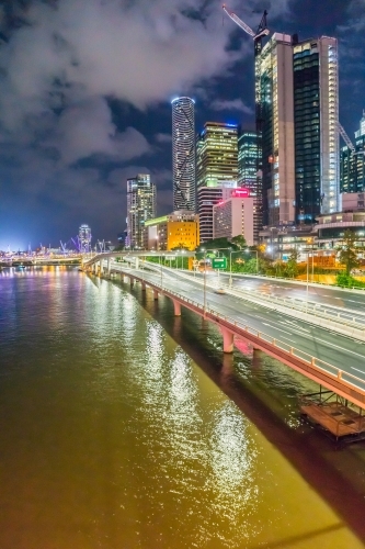 City skyscrapers along side freeway bridges over a the Brisbane River at night - Australian Stock Image