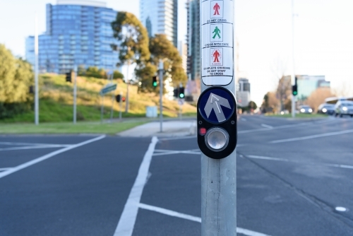 City traffic concept: Pedestrian press to go button at intersection, urban background