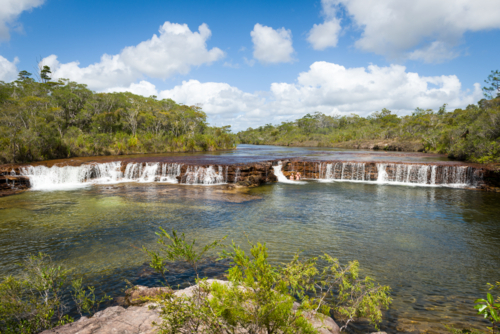 Clear waters cascading over the rock ledge at Fruit Bat Falls - Australian Stock Image
