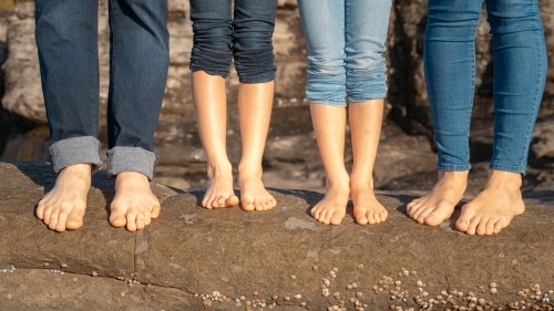 Close of family of four feet on the rocks at beach