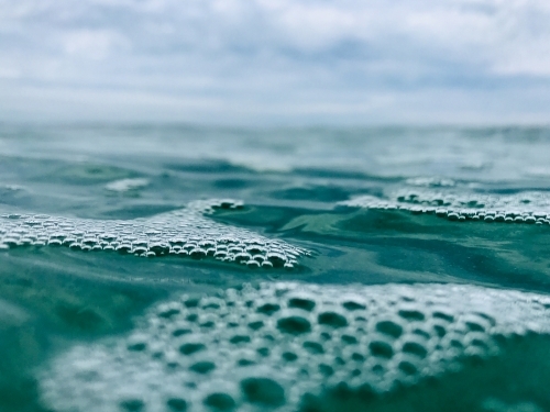 Close up Bubbles on Surface of ocean with overcast sky in background