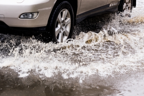 close up detail of an unrecognisable car travelling through dangerous flood water - Australian Stock Image