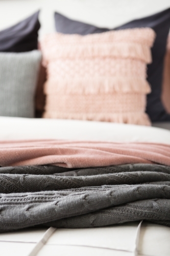 Close up detail of grey and pink throw rugs vertical - Australian Stock Image