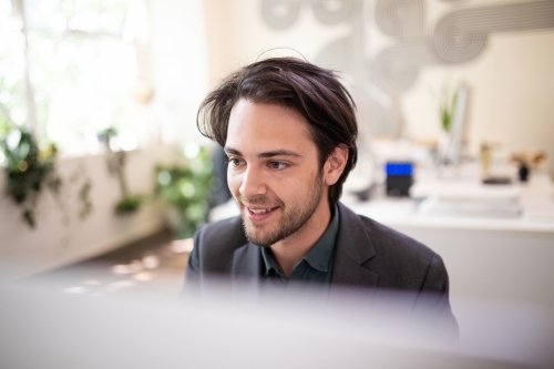 Close-up of 20-something male looking at computer screen - Australian Stock Image